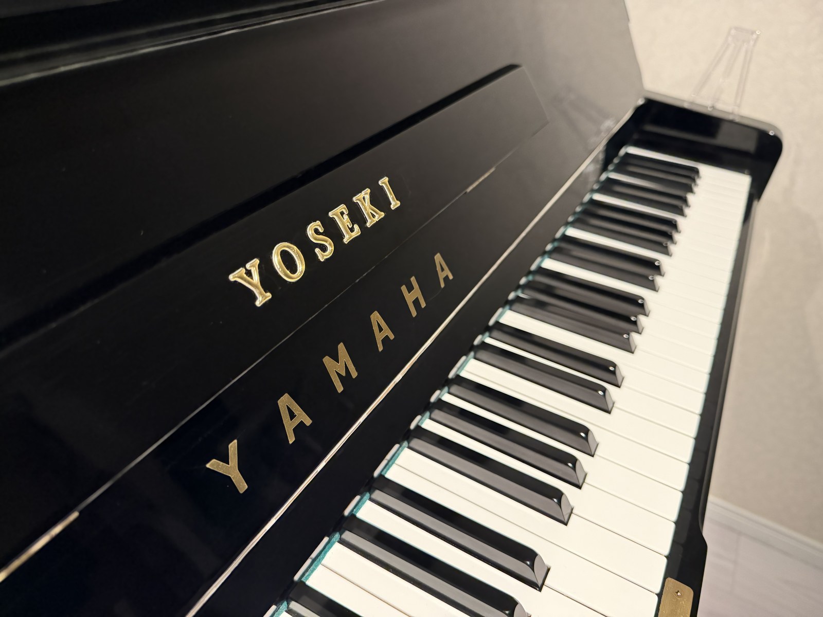 ピアノに金文字で刻まれた「YOSEKI」のロゴと鍵盤のクローズアップ